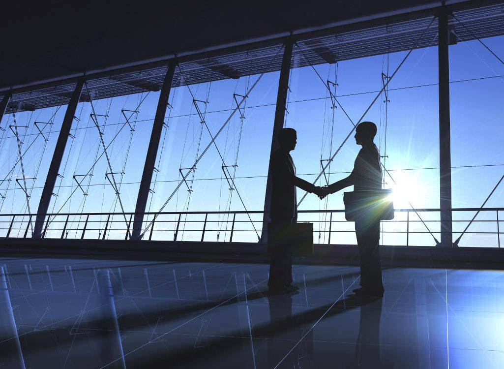 Two businessmen shaking hands in new office space.